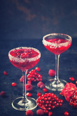 Red alcoholic cocktail with raspberry and pomegranate, in a glass glass on a black background.  Toned image. Vintage style.selective focus.