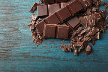 Black chocolate pieces on color wooden background