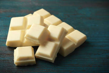 White chocolate pieces on color wooden background