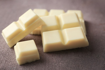White chocolate pieces on color wooden background