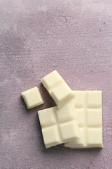 White chocolate pieces on color wooden background