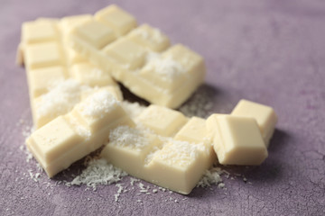 White chocolate pieces and coconut shavings on color wooden background
