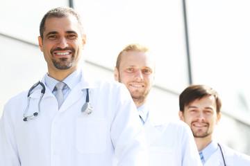 Handsome smiling doctors standing in a row near the clinic