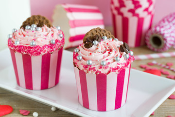 Two frosted pink cupcakes with decoration