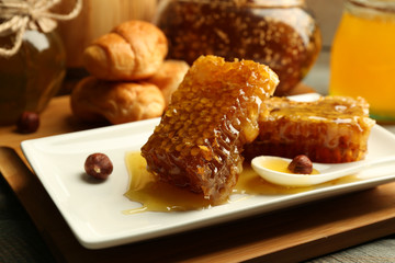 Honeycombs and spoon on plate on bright background