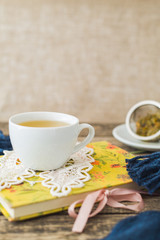 White cup of chamomile tea and book on table.
