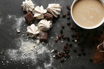 Cup of coffee and sweets on black wooden background