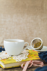White cup of chamomile tea and book on table.