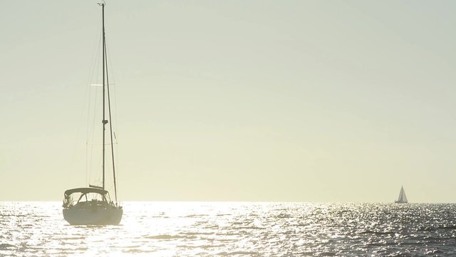 Sailing boat stopped on the sea, reflections at dusk
