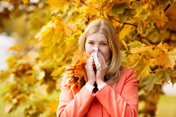 Girl with cold rhinitis on autumn background. Fall flu season. I