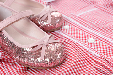 Shiny pink shoes on red plaid shirt background, close up
