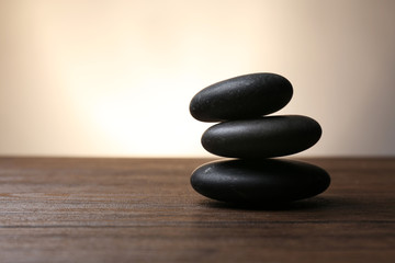 Obraz na płótnie Canvas Black pebbles on wooden table
