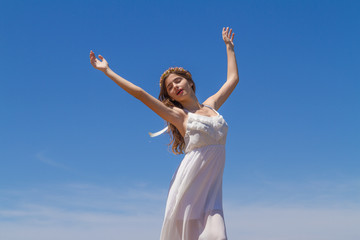Obraz na płótnie Canvas Young brunette in white flimsy dress enjoys the summer sun.
