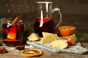 Mulled wine in glass bank with fruits and jug on decorated wooden table