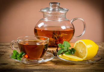 Cup and teapot of tea with mint leaf and lemon