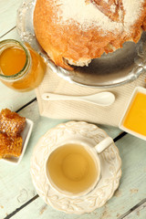 Honeycomb, bowl with honey, cup with herbal tea on color wooden background