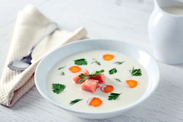 Delicious cream soup with salmon and carrot in white bowl
