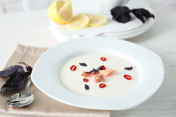 Delicious cream soup with fish and basil on white served table in the restaurant