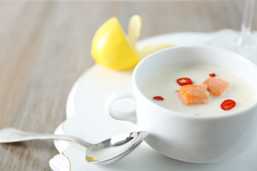 Tasty salmon cream soup, wine and lemon on wooden table, close up