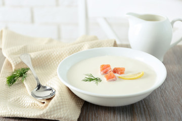 Delicious cream soup with fish and sliced lemon on wooden table