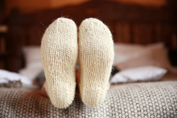 Legs of woman in warm socks on bed