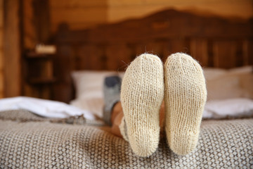 Fototapeta na wymiar Legs of woman in warm socks on bed