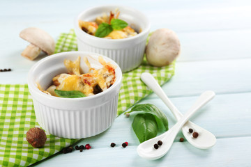 French dish julienne. Mushroom, chicken and cheese gratin in ceramic bowls, on wooden background