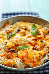 Roasted mushrooms, chicken and cheese gratin in pan, on wooden background