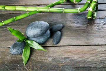 Spa stones and bamboo branch on wooden background