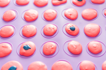 Aerial view at homemade french pink macarons on baking sheet. Silicon mat with traditional...