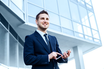 Businessman using a digital tablet computer, standing in front of his office.