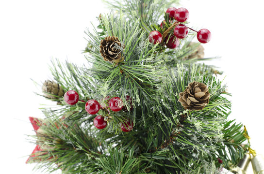 closeup image of artificial green christmas tree with red cherry and pinecone isolated on white background