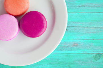Macarons in plate on vintage blue color wooden background