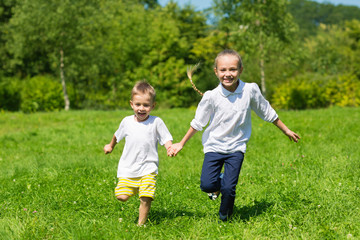 Happy brother and sister running in the autumn park