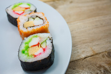 Sushi maki on a plate over wooden table