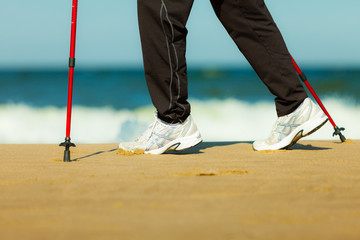 Fototapeta na wymiar Nordic walking. Female legs hiking on the beach.