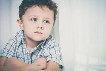 Portrait of sad little boy sitting near the window