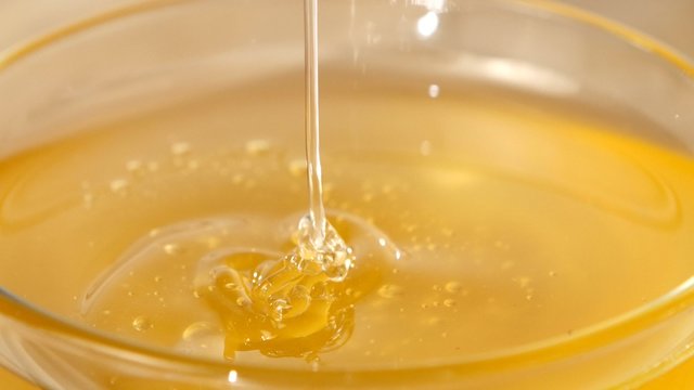 Using spoon for honey in bowl, pick it up, close up