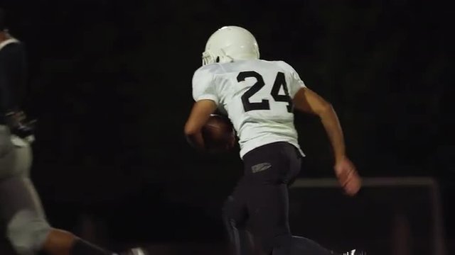 A football player runs and makes a touchdown, in slow motion