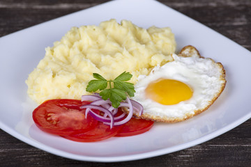Mashed potatoes with fried eggs and tomato