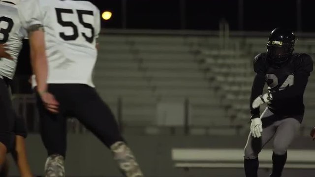A football player fights his way down the field toward the end zone at night