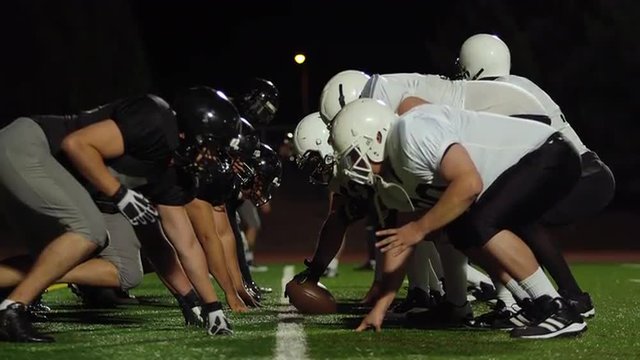 A football player gets tackled and trips over an opponent on his way to the end zone at night