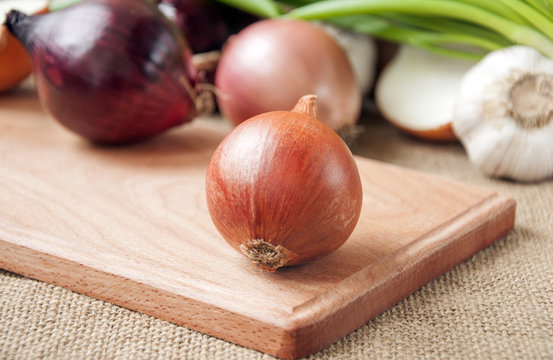  Various onions on a board on a background sacking, burlap