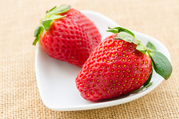 Ripe red strawberries in white cup.