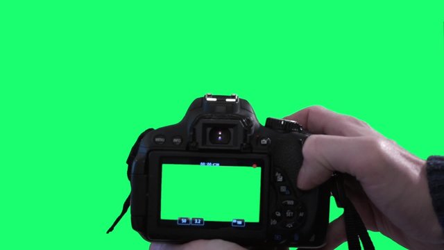 Filming with dslr camera on green screen background. Close shot of a hand filming with a dslr camera on a green screen background.