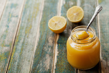 Lemon curd in glass jar on rustic wooden table, traditional fruit cream, vintage style