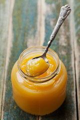 Lemon curd in glass jar on rustic wooden table, traditional fruit cream, vintage style