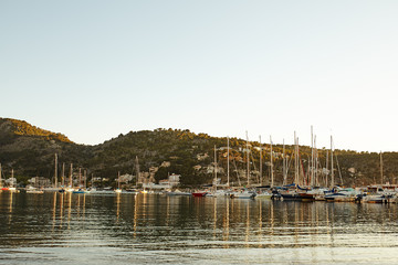 Sunset in Port Soller with docked yachts and boats. Houses on hillside of Puerto de Soller. Majorca, Spain.