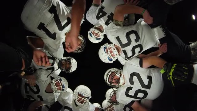 Low angle view looking up at football players inside a huddle