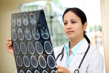Female doctor examining a brain computerized tomography scan - 95615176